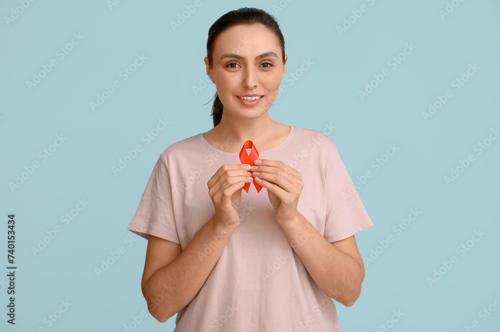 Young woman with red ribbon on blue background. AID awareness concept Young woman with red ribbon on blue background. AID awareness concept