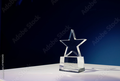 Star-shaped award made of glass on a white table with a spotlight on it and copy space