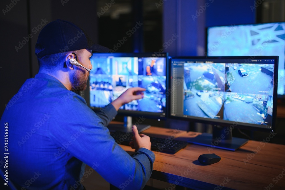 Security operator controls CCTV cameras in office at night. Modern security system and social safety concept Security operator controls CCTV cameras in office at night. Modern security system and social safety concept