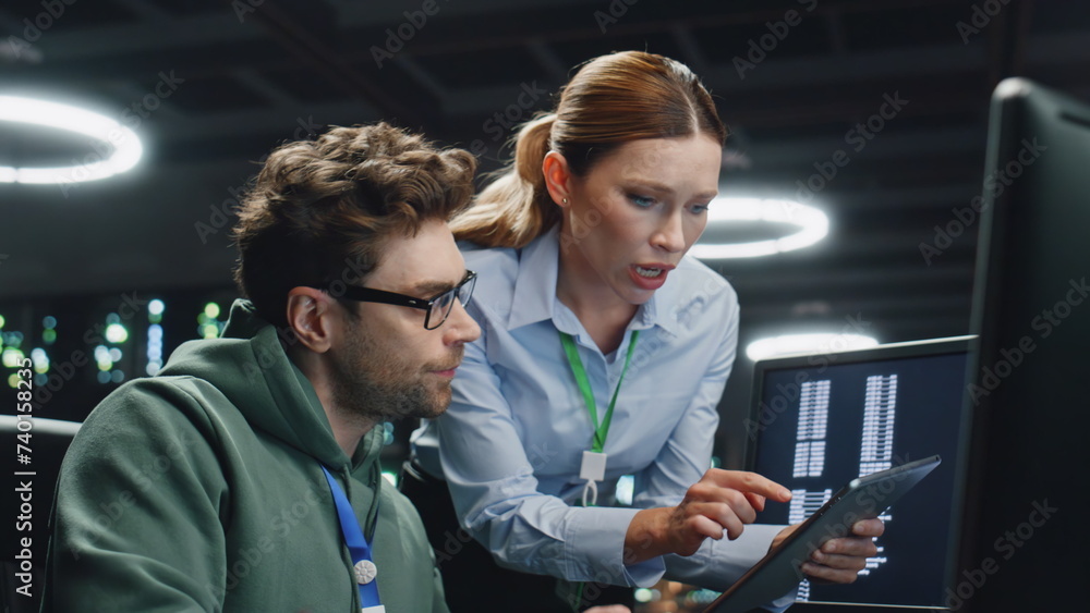 Data center analysts working in server room closeup. IT specialist showing data Data center analysts working in server room closeup. IT specialist showing data