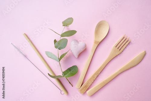 Zero waste concept, reusable eco-friendly straw and wooden cutlery over pink background photo