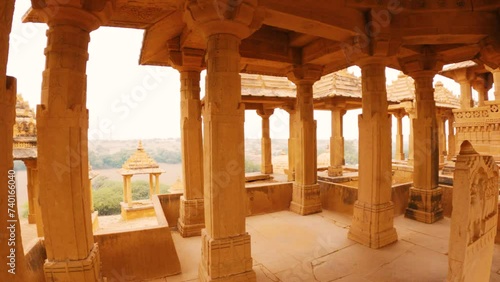 4K moving shot of pillars of the cenotaphs and Royal Chhatris in Thar desert at Jaisalmer, Rajasthan, India. View of desert from inside cenotaphs of Bada Bagh. Historical Indian architecture. photo