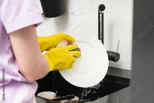 Close-up shot of a woman washing dishes in the kitchen. Household and cleaning concept