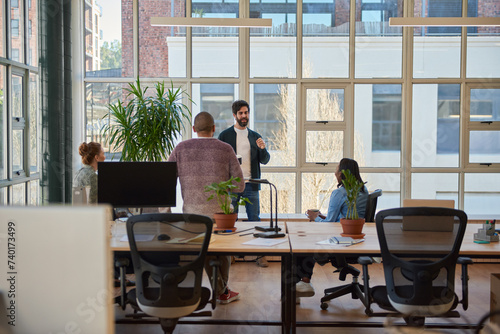 Young businessman talking with colleagues over coffee in an office