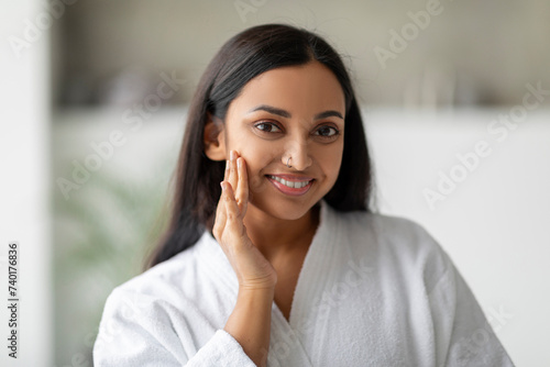 Pretty indian woman in white bathrobe posing at white bathroom
