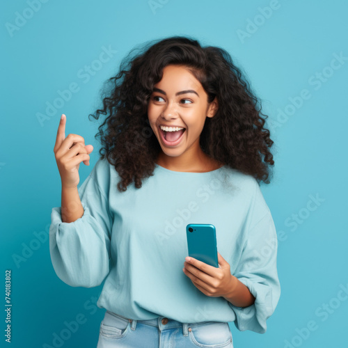 An excited woman holding mobile phone; on blue background 