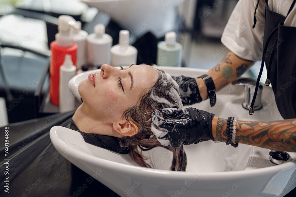 Close up of female barber washes the hair of woman in beauty salon Close up of female barber washes the hair of woman in beauty salon