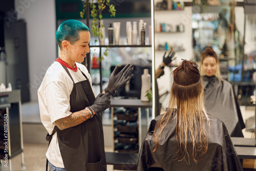 Professional colorist putting on gloves before coloring hair in beauty salon