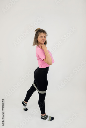 European woman wear sportclothes doing pilates workout with rubber bands isolated on white
