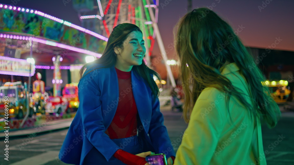 Obraz premium Happy best friends embracing meeting at amusement park. Smiling girls resting