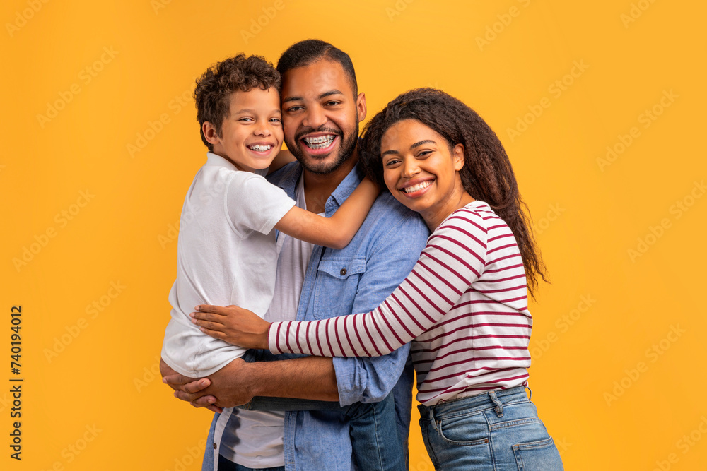 Heartwarming family portrait with black preteen boy cuddling with parents Heartwarming family portrait with black preteen boy cuddling with parents
