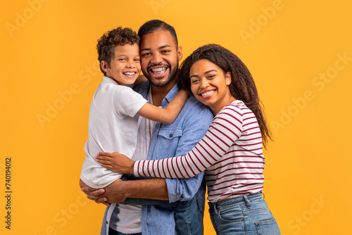 Heartwarming family portrait with black preteen boy cuddling with parents © Prostock-studio