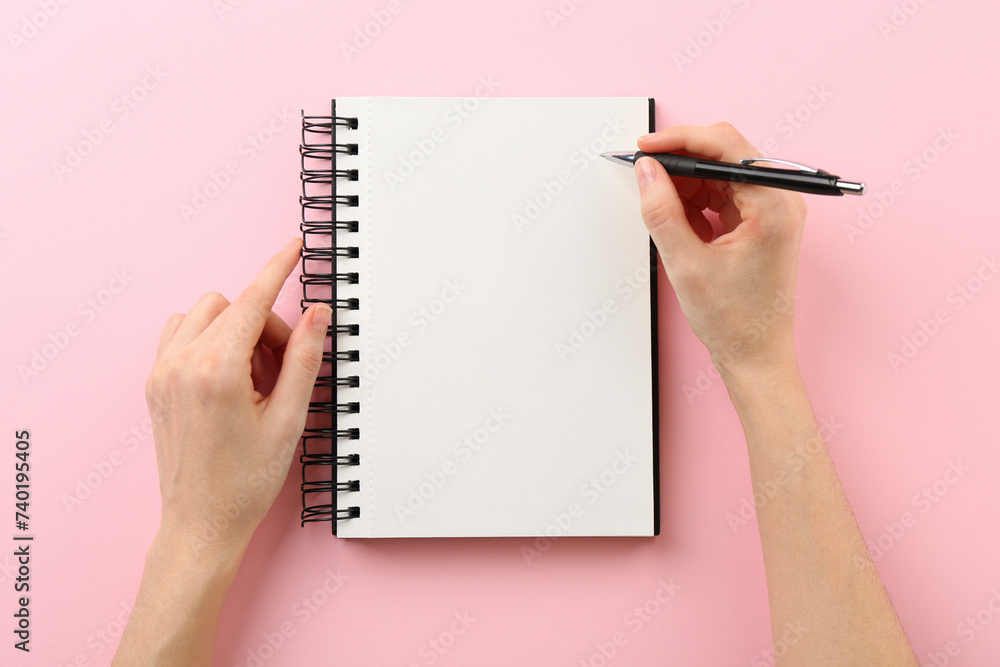 Woman writing in notebook on pink background, top view Woman writing in notebook on pink background, top view