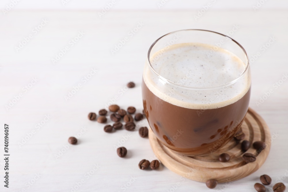 Refreshing iced coffee with milk in glass and beans on white table, closeup. Space for text Refreshing iced coffee with milk in glass and beans on white table, closeup. Space for text