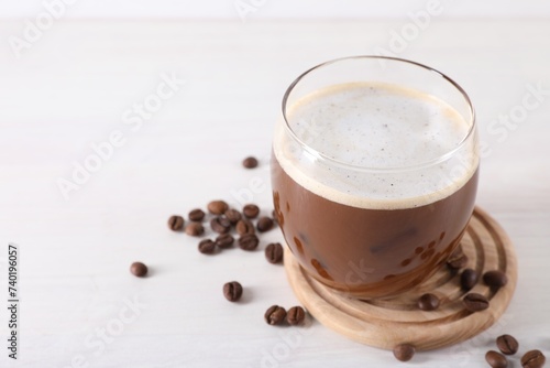 Fototapeta Naklejka Na Ścianę i Meble -  Refreshing iced coffee with milk in glass and beans on white table, closeup. Space for text