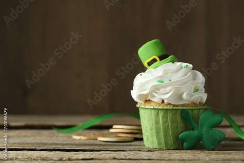 St. Patrick's day party. Tasty cupcake with green leprechaun hat topper on wooden table, closeup. Space for text