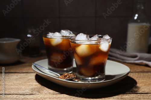 Refreshing iced coffee in glasses, ingredients and spoon on wooden table
