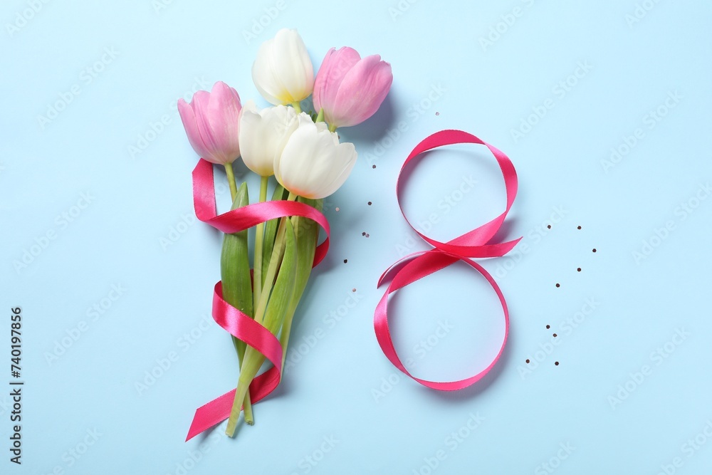 8th of March greeting card design with pink ribbon and beautiful flowers on light blue background, flat lay. International Women's day
