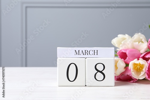 International Women's day - 8th of March. Wooden block calendar and beautiful flowers on white table, space for text
