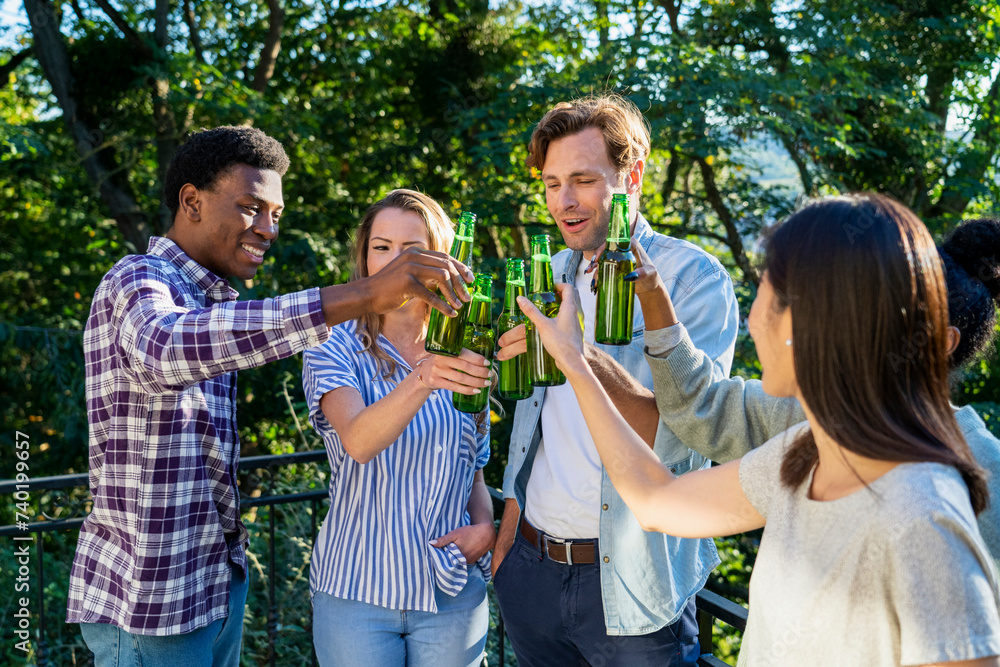 Group of friends toasting with beer bottles standing outdoors Group of friends toasting with beer bottles standing outdoors