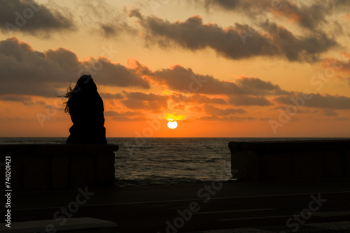 Una ragazza che guarda il tramonto a Marina di Ragusa