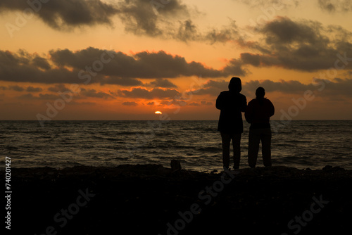 Due persone osservano il tramonto a Marina di Ragusa