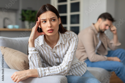Worried young woman with upset man in background