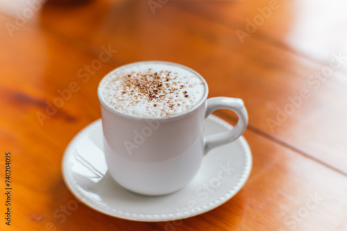 Cappuccino coffee with cinnamon powder, served in a white cup, freshly ground from the recent harvest.