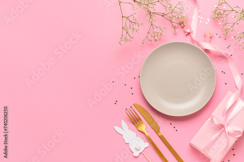 Festive Easter table setting decorated with gifts and eggs on pink background
