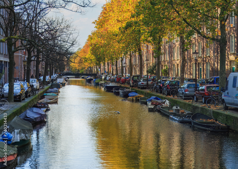 Famous Amsterdam city center canal  with dutch brick buildings, trees , reflections  and  anchored boats in sunny autumn day. Netherlands