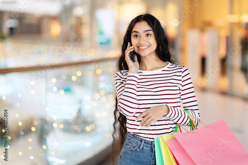 Emotional hindu woman walking by shopping mall, talking on phone