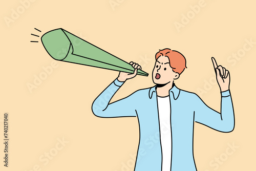 Man protests against unfair distribution money in society and class inequality, holding paper megaphone in hands. Guy protests after learning about increase in taxes or reduction in social benefits