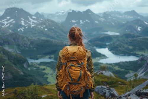 Amidst a sea of rolling clouds, a lone woman gazes upon the vast and majestic mountain range before her, her trusty backpack by her side as she embarks on a journey through the rugged and breathtakin
