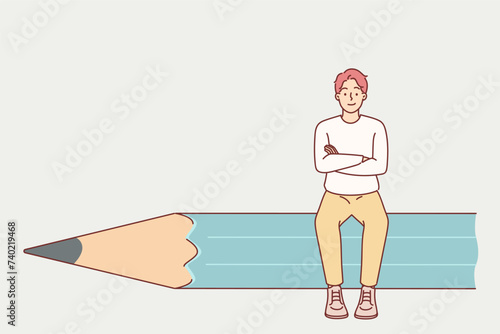 Man designer sits on giant pencil and crosses arms in front of chest, demonstrating confidence