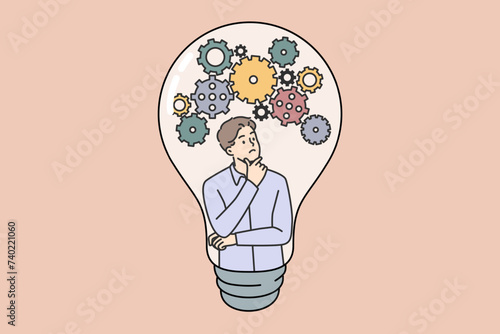 Thoughtful guy comes up with new idea scratching chin and looking at gears inside light bulb. Smart guy developing idea to launch successful unicorn startup or thesis for university