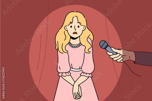 Little girl is afraid to speak in front of public and feels embarrassed standing on stage near hands with microphone. Afraid of public speaking and lack of oratory skills fetters female teenager