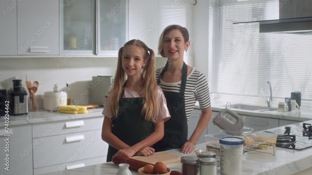 Medium copy space portrait shot of Caucasian mother and daughter smiling at camera when cooking together at kitchen Medium copy space portrait shot of Caucasian mother and daughter smiling at camera when cooking together at kitchen