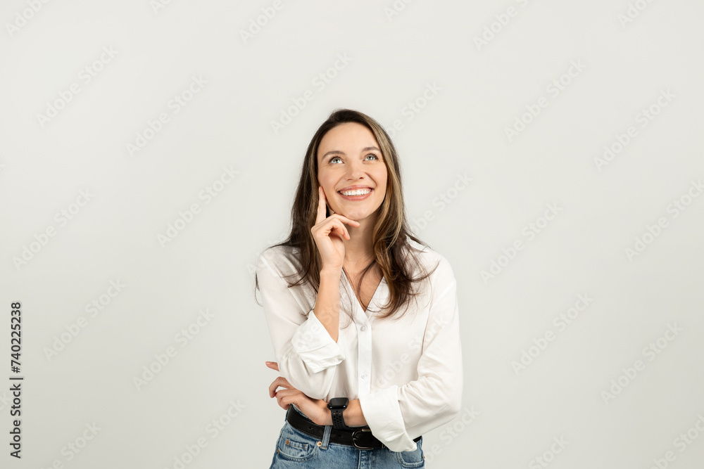 Happy young woman with long brown hair, wearing a white shirt and blue jeans
