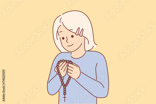 Little christian girl holding rosary with cross and praying, concept receiving religious education