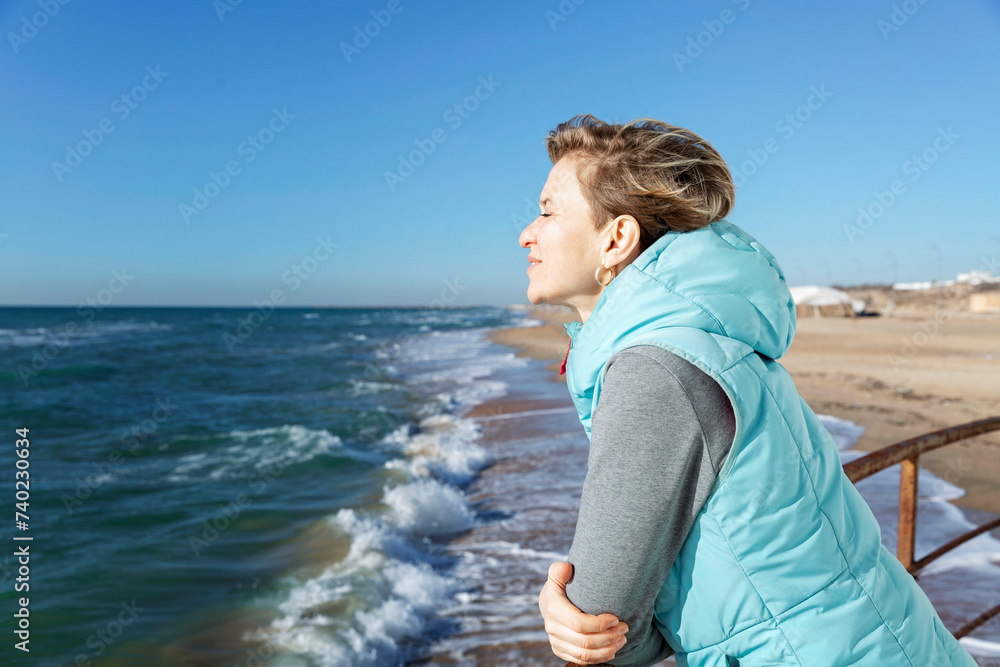 A young woman walks along the sandy seashore in the winter season on a sunny day. Holidays at the resort in the off-season.