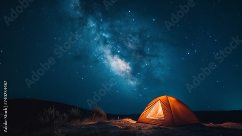 A lonely tent with a cozy light inside under the starry sky. Sleeping under the stars, the romance of travel, the grandeur of nature