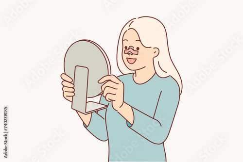 Happy woman after rhinoplasty surgery on nose looks in mirror and rejoices at improvement own image