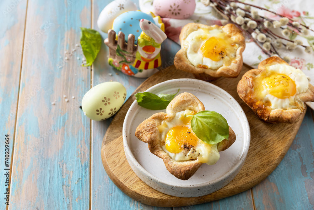 Scrambled eggs in puff pastry with cheese and bacon. Easter breakfast on a festive table. Copy space. Scrambled eggs in puff pastry with cheese and bacon. Easter breakfast on a festive table. Copy space.