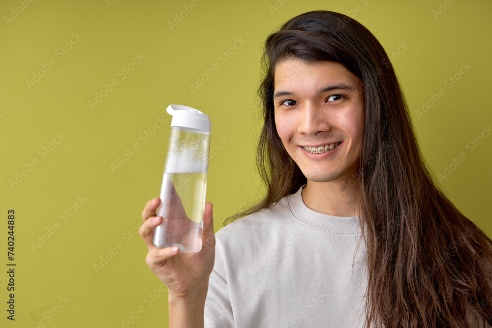 hispanic man wearing casual shirt holding bottle of fresh water, very happy, copy space for advertisement. healthy lifestyle, people. male with long dark hair look at camera isolated on green hispanic man wearing casual shirt holding bottle of fresh water, very happy, copy space for advertisement. healthy lifestyle, people. male with long dark hair look at camera isolated on green