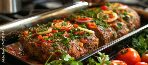 A tray of Uzbek meat loaf, garnished with tomatoes and parsley, showcasing a delicious combination of vegetables, meat, and spices.