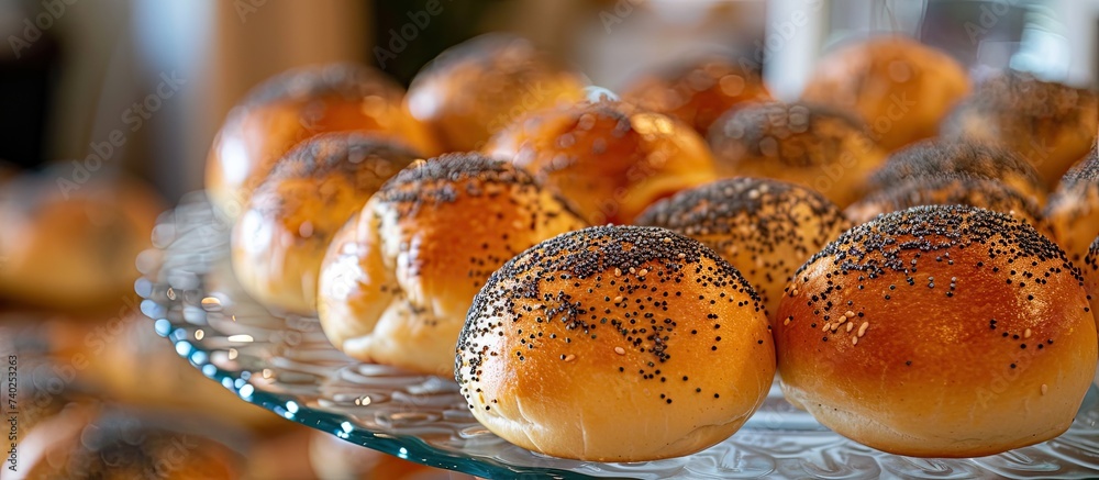 A detailed view of poppy seed buns arranged on a glass plate on a buffet table.