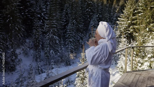 A woman in a terry robe drinks tea on the terrace