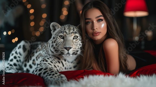 a female with long brunette hair, she is lying on a bed and a white leopard is next to her, dark black and red room