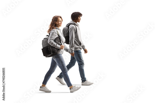 Full length profile shot of an african american guy walking and holding hands with a caucasian young woman