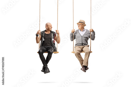 Punk and a senior man sitting on swings and looking at each other